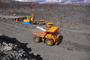 Obraz premium Heavy truck pours the road with water in the iron ore quarry. Dust removal, protection of the environment. Irrigation of the road from dust 