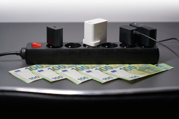 black power strip with chargers and euro banknotes (100), symbolizing increase of electricity...