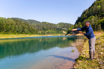 A young fisherman in lake with his fishing rod