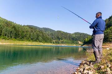 A young fisherman on the river catching a fish with his fishing rod