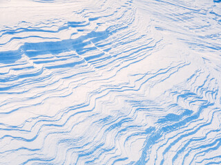 Beautiful winter background with snowy ground. Natural snow texture. Wind sculpted patterns on snow...