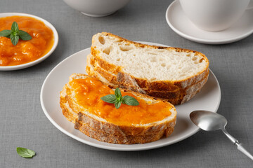 Sandwich with apricot jam and mint on a gray table. Tasty breakfast