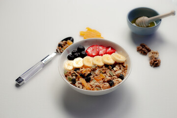 Healty breakfast.Healthy granola bowl with strawberries.Bowl of honey,wallnuts .Healthy lifestyle.Healthy fruits.Kitchen in background.Wooden spoon
