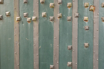 A close up of a weathered wooden door with metal accents