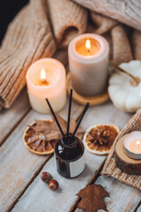 Home comfort, coziness, aromatherapy. Cozy interior with knitting, burning candles and aroma perfume diffuser in the living room. Fall scent, sweet pumpkin pie fragrance, dry leaves, autumn mood