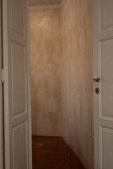 A glimpse into a room with tiled walls and a wooden floor The door is slightly ajar revealing the space beyond