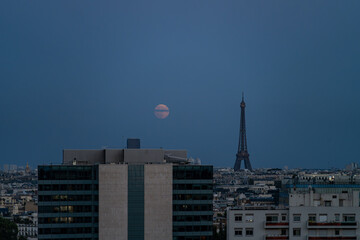 Distant view of Eiffel Tower in a with full moon in blue sky at dusk