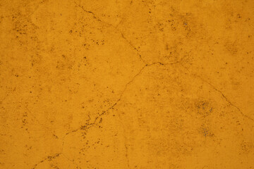 A close up of a yellow wall with subtle cracks