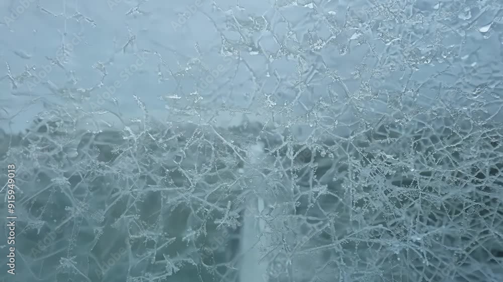Poster A detailed view of frost forming on a windowpane showcasing the delicate ice patterns and textures.