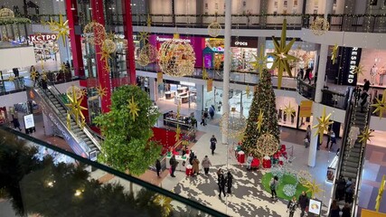 Festive shoppers in modern mall atrium with christmas decorations