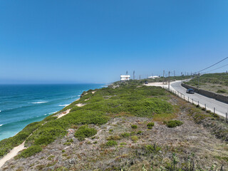 Coastal road winding along a rugged coastline with crashing waves in the distance