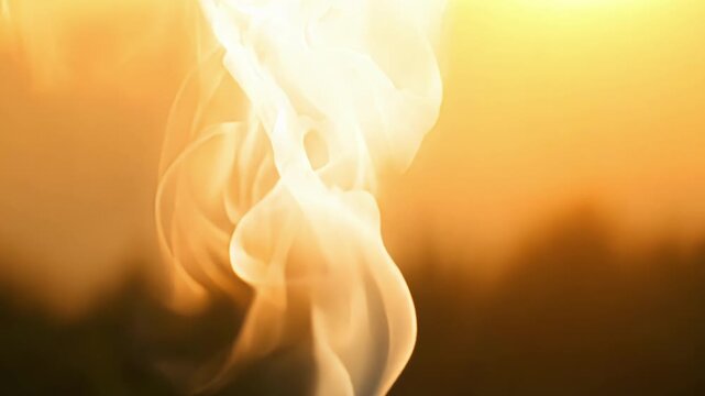 A closeup shot of smoke illuminated by the sun appearing almost like a living entity as it dances and swirls in the light.