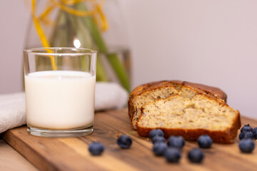 glass of milk and sweet homemade banana bread with crispy crust on a wooden board, dessert