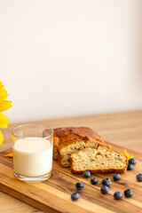 glass of milk and sweet homemade banana bread with crispy crust on a wooden board, dessert