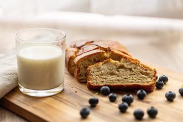 glass of milk and sweet homemade banana bread with crispy crust on a wooden board, dessert