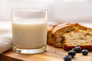 glass of milk and sweet homemade banana bread with crispy crust on a wooden board, dessert