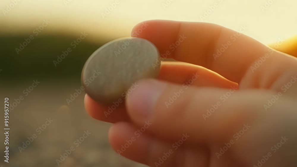 Poster low angle of a childs hand picking up a smooth pebble marveling at the polished surface and rounded 