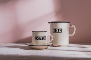 Rustic enamel Coffee Cup and Milk Jug on wooden table.  window morning light.