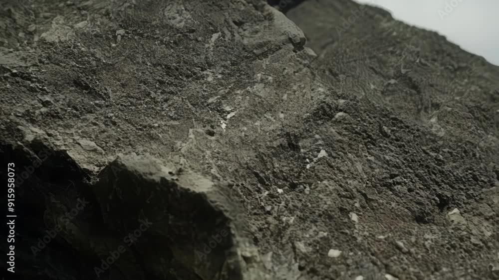 Poster In this closeup footage a volcanic rock is seen from a unique angle showcasing its sharp and craggy edges in sharp detail. The rocks surface is covered in tiny intricate lines and