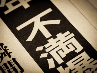 「不満」と書かれたニュースの見出し