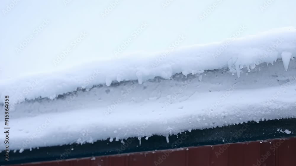 Aufkleber A snowy rooftop where the snow is piling up in distinct layers with some melting and dripping down the sides.