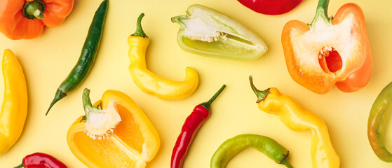 Different fresh peppers on yellow background