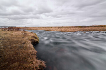 Long exposure of a river flowing through a grassy plain in iceland