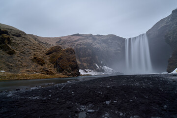 Skogafoss waterfall cascading into icy river in iceland