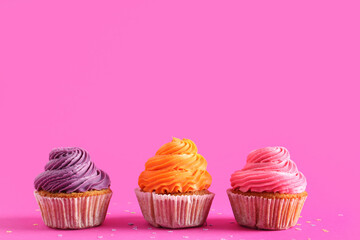 Tasty colorful cupcakes on pink background