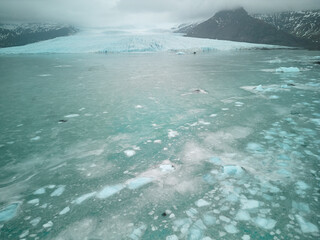Glacial lagoon water with melting icebergs and mountain background