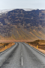 Empty asphalt road leading towards mountain range in iceland