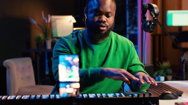 Musician doing online paid classes to help people play piano notes, teaching lessons from his home studio and recording video tutorials. Musical instructor playing midi controller keyboard. Camera A.