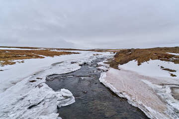 Scenic view of a river flowing through a beautiful snowy landscape in iceland