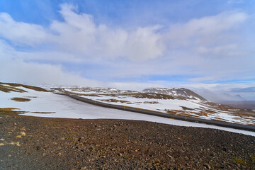 Empty road crossing snowy landscape in iceland during spring