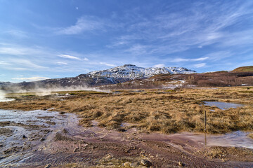 Geothermal field steaming with volcanic activity under blue sky
