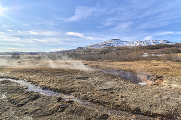 Geothermal area releasing steam under blue sky in iceland