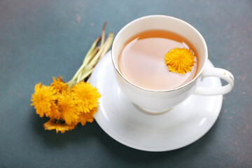 Cup of healthy dandelion tea on dark background