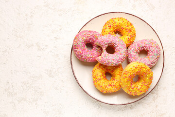 Plate with sweet donuts on light grunge background
