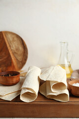Wooden board with fresh lavash on light background