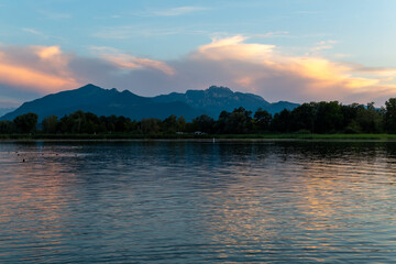 Beautiful evening at the shores of Chiemseestrand in Bavaria. The calm lake, colorful sky, and...