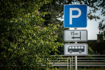Fototapeta premium A bus parking sign showing a 15-meter designated area, set against a backdrop of lush green trees. The blue and white sign is clearly visible, directing bus drivers to the parking spot in a rural
