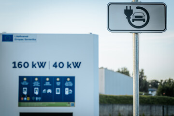 A sign indicating an electric vehicle charging station is shown alongside a charging unit...