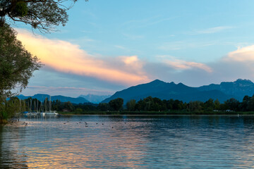 Beautiful evening at the shores of Chiemseestrand in Bavaria. The calm lake, colorful sky, and...