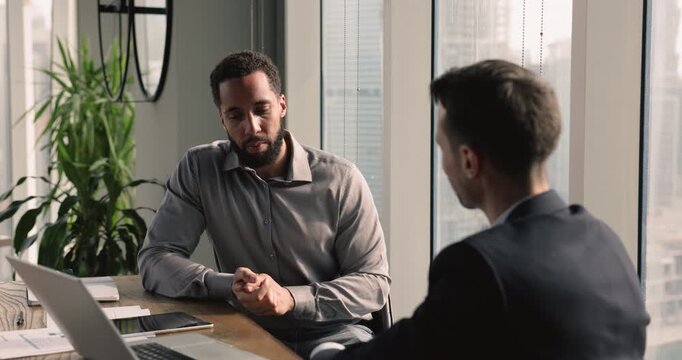 The multiethnic businessmen engaged in discussion met in office boardroom. African boss make speech, tell about upcoming project, express opinion to overcome potential challenge. Teamwork, negotiation