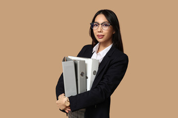 Portrait of young Asian businesswoman with office folders on beige background