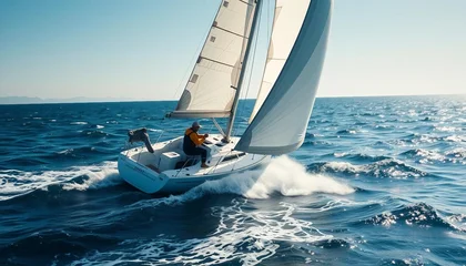 Fotobehang A sailboat races across the open sea in bright sunlight, with a competitive sailor adjusting the sails to harness the wind, as waves churn beneath and the wind whips through the sails. © abu
