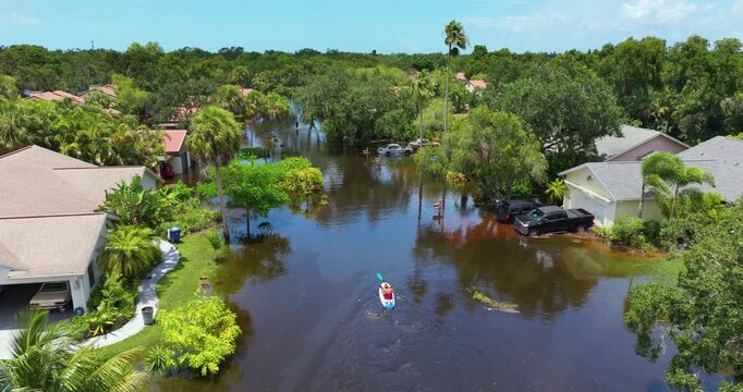 Person kayaking between hurricane Debby flooded homes in residential community in Sarasota, Florida. Aftermath of natural disaster