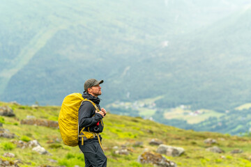 male hiker in the fjord of Andalsnes - Isfjorden in Norway hiking on a rainy cloudy day in the mountains of Massvassbu