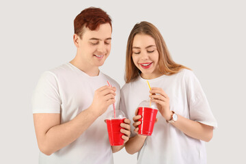 Happy young couple drinking cola on white background