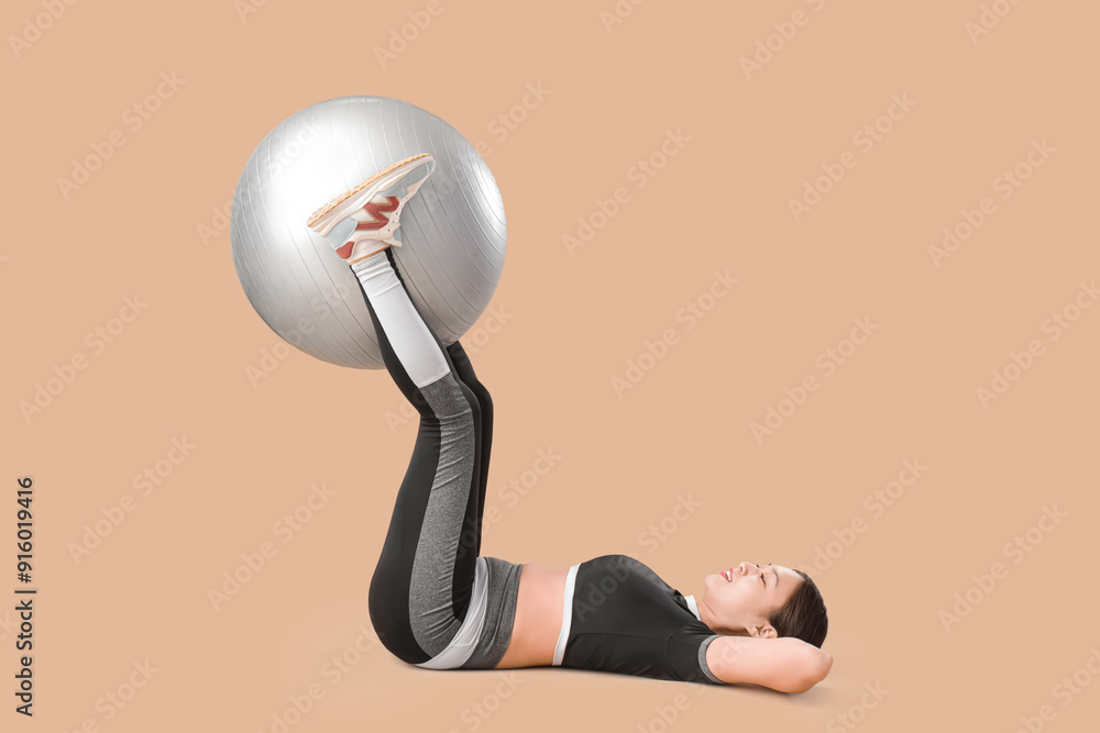 Poster Sporty young Asian woman exercising with fitball on beige background